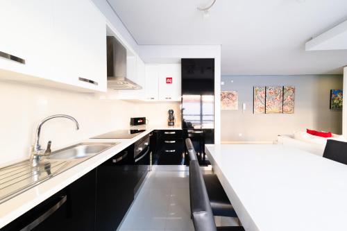 a kitchen with black and white cabinets and a sink at Luxury Apartments Baleal in Baleal