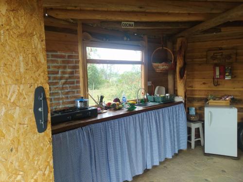 a kitchen with a counter in a cabin with a window at Eco-cabaña piemonte in Guasca