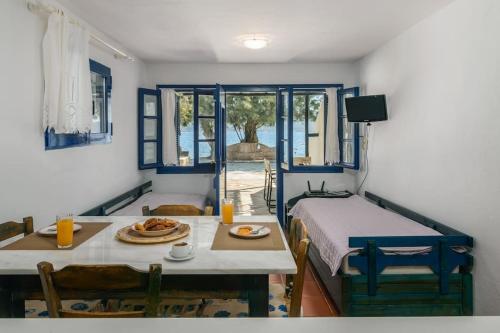 a room with a table and a bed and a table and chairs at Skinopi Beach Guesthouse in Schinopi
