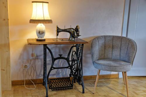 a table with a sewing machine and a chair at Chez Jeanne, charmante maison in Dossenheim-sur-Zinsel