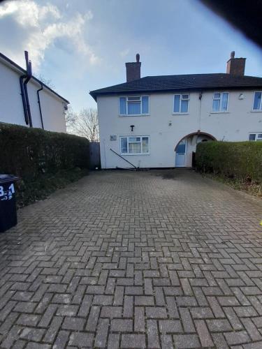 a white house with a brick driveway in front of it at Welcoming Home Close to Transport Links in Thornton Heath