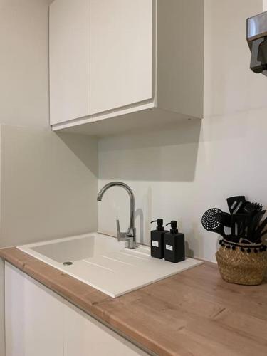 um balcão de cozinha branco com um lavatório e uma torneira em Appartement central à Castelnaudary em Castelnaudary
