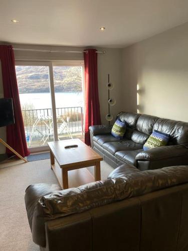 a living room with a leather couch and a table at Fassifern. 1st Floor Apartment with Loch View in Fort William