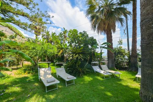 un groupe de chaises et de palmiers dans l'herbe dans l'établissement Hotel Baia Delle Sirene, à Taormine