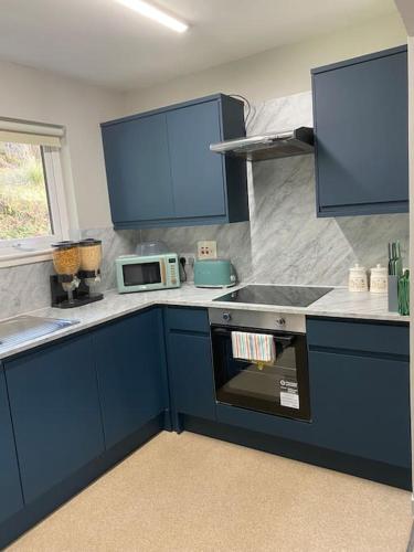 a kitchen with blue cabinets and a stove top oven at Fassifern. 1st Floor Apartment with Loch View in Fort William