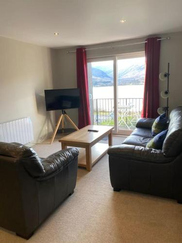 a living room with two leather couches and a table at Fassifern. 1st Floor Apartment with Loch View in Fort William