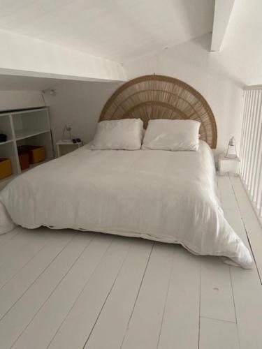 Elle comprend un grand lit blanc avec des draps et des oreillers blancs. dans l'établissement Appartement vue mer, accès privé plage, piscine, à Sainte-Maxime