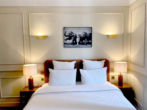 una camera da letto con un letto con lenzuola bianche e due lampade di Hôtel Bristol Pau a Pau