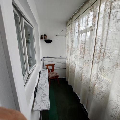 einen Flur mit einem Stuhl und ein Fenster mit Vorhängen in der Unterkunft Apartament central 2 camere in Eforie Nord