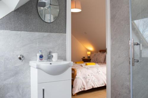 een badkamer met een wastafel en een bed bij Tudor Cottage Manorbier in Manorbier