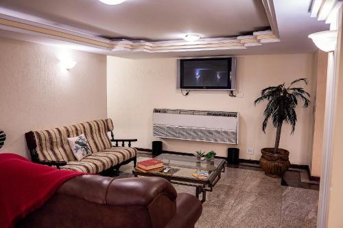a living room with a couch and a tv at Sakr Hotel in Penápolis