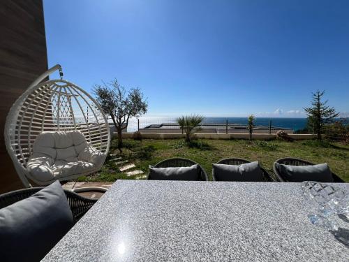 a table and chairs with a swing and the ocean at MUMBAS APARTMENT DHERMI in Gjilek