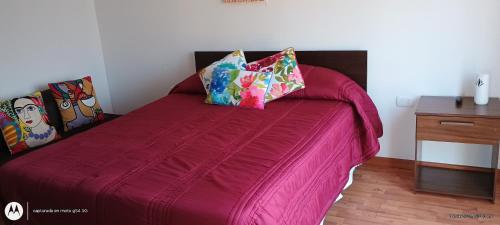 Una cama rosa con dos almohadas encima. en Se arrienda departamento en caldera, en Caldera