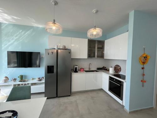 a kitchen with a refrigerator and white cabinets and lights at MUMBAS APARTMENT DHERMI in Gjilek