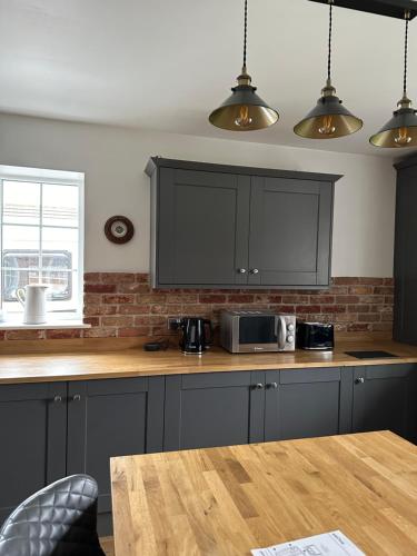 a kitchen with black cabinets and a wooden table at The Hidden Snug Cottage in Knaresborough