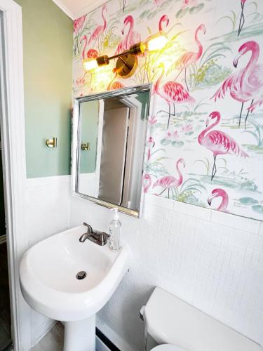 baño con lavabo y papel pintado de flamencos rosa en The Hollywood Suite Downtown, BeverlyHills Vibe, en Fredericton