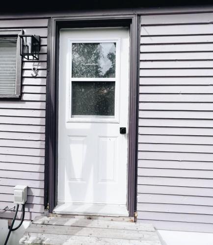 a white door with a window on a house at Cottage Feels in the City - Downtown Apartment & Backyard Bliss in Fredericton