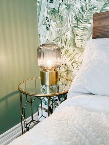 a gold lamp on a glass table next to a bed at The Hollywood Suite Downtown, BeverlyHills Vibe in Fredericton