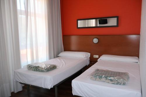 two beds in a room with an orange wall at Loop INN Hostel Santiago de Compostela in Santiago de Compostela