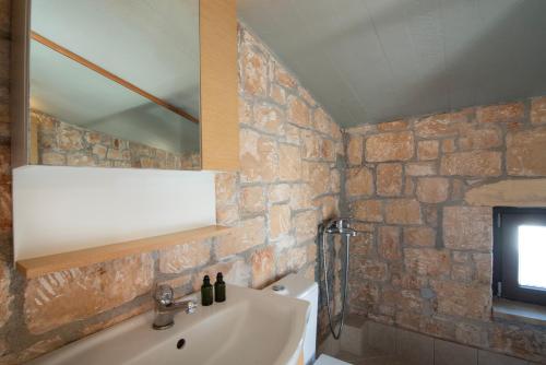 uma casa de banho com um lavatório e uma parede de tijolos em Mira Mare em Khlóï