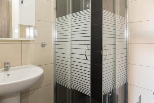 ケラモティにあるTzamtzis Apartmentsのバスルーム(洗面台、ガラス張りのシャワー付)