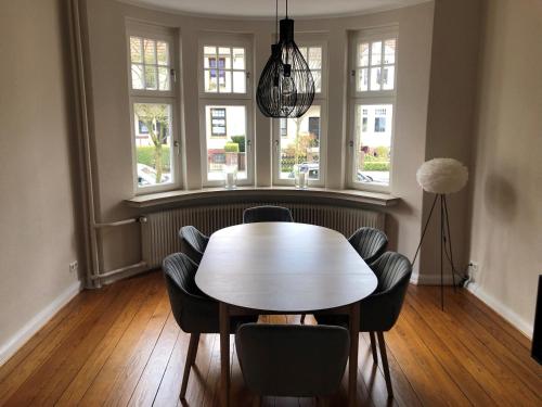 comedor con mesa, sillas y ventanas en Ferienhaus ON90, en Wilhelmshaven