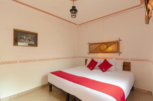 1 dormitorio con cama blanca y almohadas rojas en OYO Hotel Coyopolan, en Xico