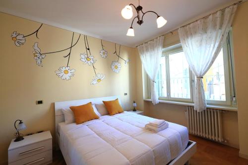 DA MEGGY في ستريزا: غرفة نوم مع سرير أبيض مع زهور على الحائط