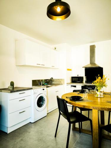 - une cuisine avec une table et un lave-linge/sèche-linge dans l'établissement L'instant aixois T3 situé à Aix La Duranne, à Aix-en-Provence