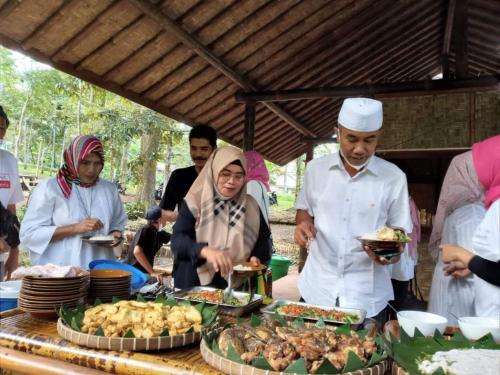 a group of people standing around a table with food at Joben Evergreen Camp in Tetebatu