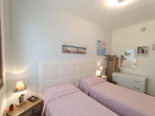 サン・ヴィート・ロ・カーポにあるAppartamento Le Ginestreのベッドルーム1室(ベッド2台、ランプ付きテーブル付)