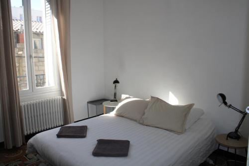 a bedroom with a white bed with two towels on it at Superbe appartement avec parking sur place in Nîmes