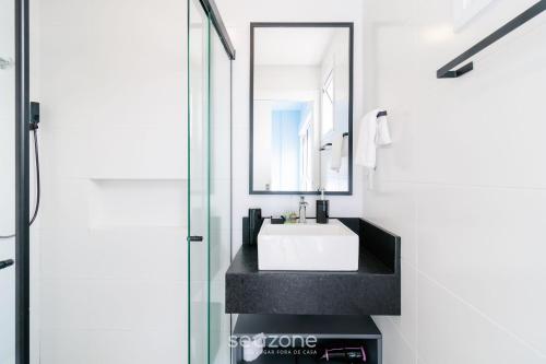 um banheiro com pia branca e espelho em Apartamentos próx a UFSC - SVE em Florianópolis