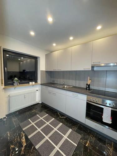 a kitchen with white cabinets and a black stove at Ferienwohnung Wilusa 2 - Self Checkin in Rheinfelden