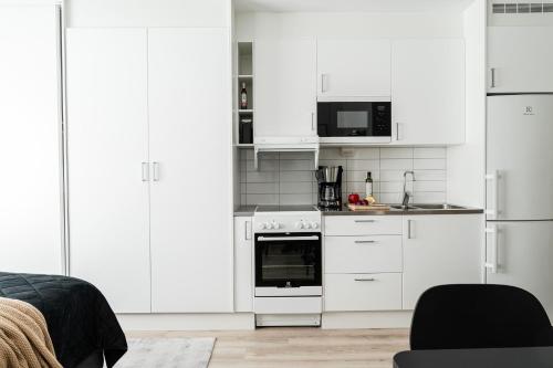 una cocina blanca con armarios y electrodomésticos blancos en Consultant's Luleå Hub: Work & Rest en Luleå