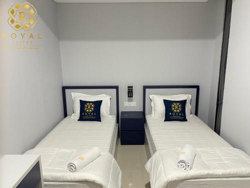 two beds in a room with white sheets and blue pillows at Apartment Pollux Habibie 2BR 11th Floor By Royal Suites in Batam Center