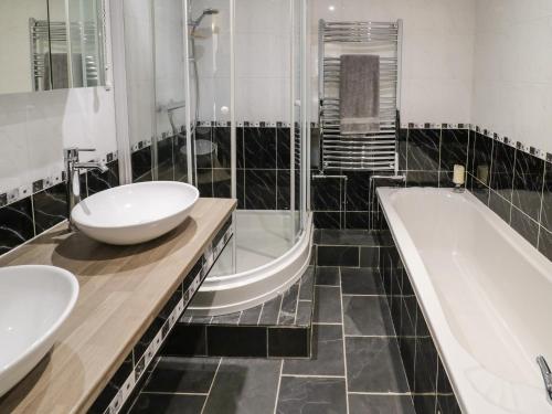 ein Badezimmer mit zwei Waschbecken und einer Badewanne in der Unterkunft Home Farm Cottage in Southam