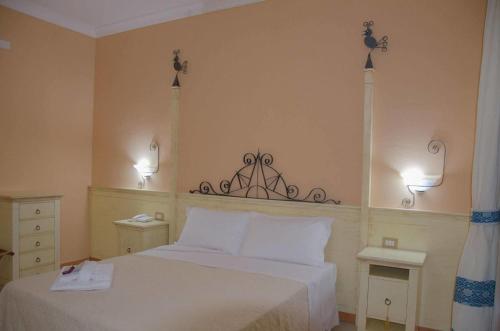 ein Schlafzimmer mit einem Bett und zwei Lampen an der Wand in der Unterkunft Hotel La Rosa dei Venti in Buggerru