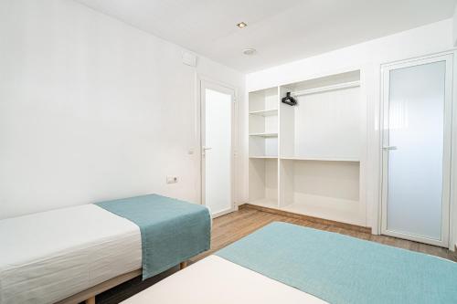 biała sypialnia z łóżkiem i niebieskim dywanem w obiekcie New Kensington Apartments - Econotels w Magaluf