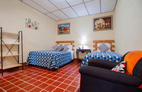 een kamer met 2 bedden en een bank bij Posada Doña Luisa in Antigua Guatemala