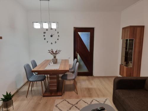 a dining room with a table and chairs and a clock at Joy Apartman in Sovata