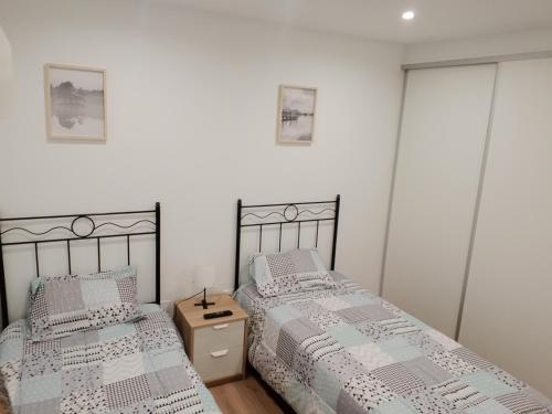 2 camas en un dormitorio con paredes blancas en Apartamento Pumarin, en Oviedo