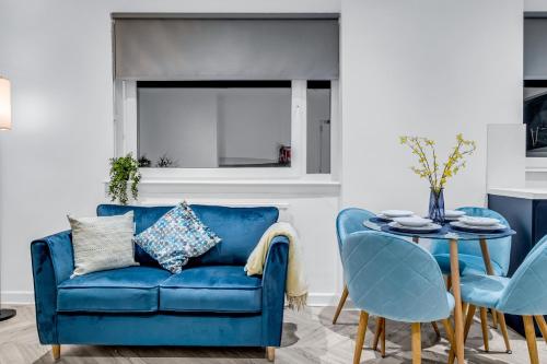Spital Stay - SJA Stays - Luxury 3 Bed Apartment في أبردين: أريكة زرقاء في غرفة المعيشة مع طاولة وكراسي