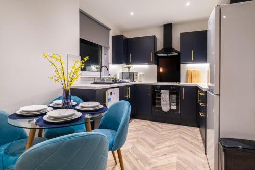 Spital Stay - SJA Stays - Luxury 3 Bed Apartment في أبردين: مطبخ مع طاولة طعام وكراسي زرقاء