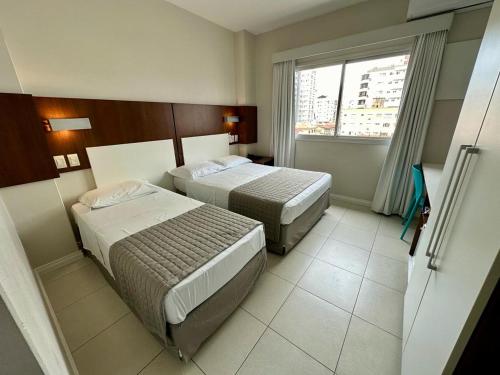 Habitación de hotel con 2 camas y ventana en Art Hotel, en Tubarão