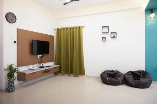 a living room with a tv and a green curtain at Classe Moyenne -2BHK, Near US Embassy, Gachibowli in Hyderabad