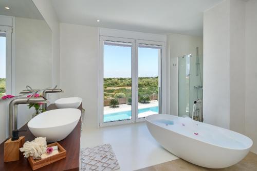 een witte badkamer met een bad en een wastafel bij Villa Es Trenc in Campos