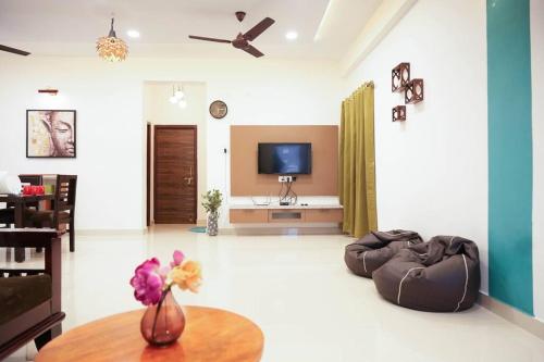 a living room with a couch and a tv at Classe Moyenne -2BHK, Near US Embassy, Gachibowli in Hyderabad