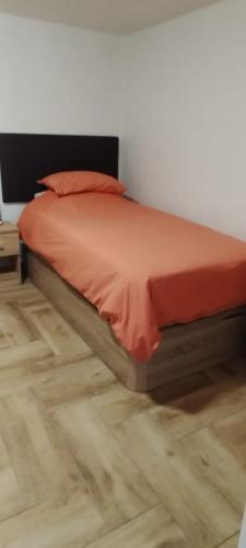 a bed with an orange comforter on a wooden floor at Casa Azul Mountain Retreat in Vega de San Mateo