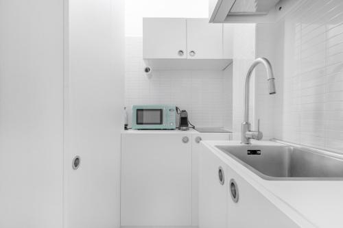 Una cocina blanca con fregadero y microondas. en Casa da Suite Stadium, en Milán